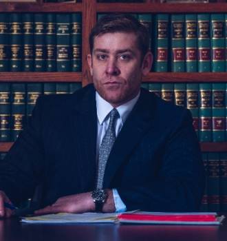 Devin McBride sitting at a table in front of a law library