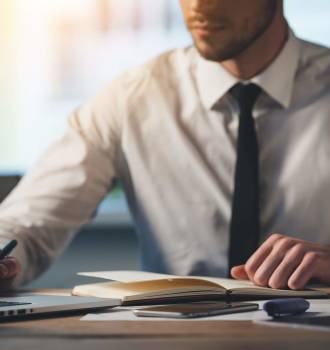 Person in dress shirt and tie writing on document