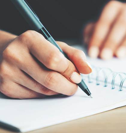 Woman writing with pen on a notebook