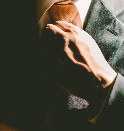 Close up of man in suit fixing his tie