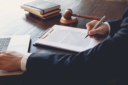 Man in suit with a clipboard, gavel, pen, books, and laptop