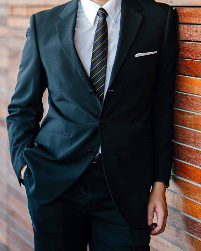 man in suit leaning against a wall