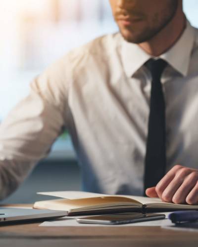 Person in dress shirt and tie writing on document