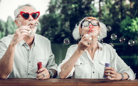 an older couple blowing bubbles with fun glasses on