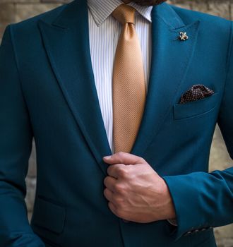 Man in suit posing in front of a wall