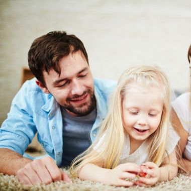 Two parents laying down with their daughter.