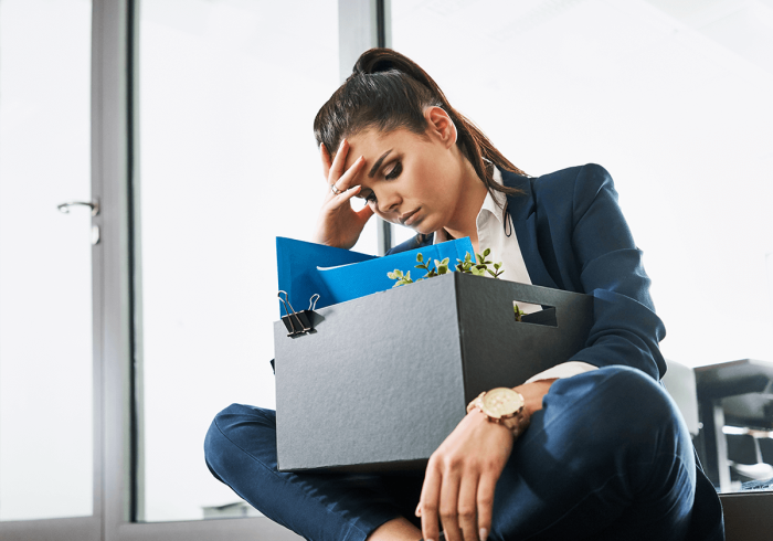 A woman sitting on the floor with a box of her work belongings.