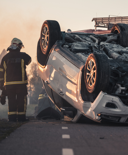 A firefighter next to a flipped over car