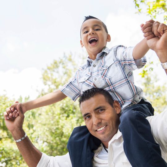 Hispanic Father with his son on his shoulders