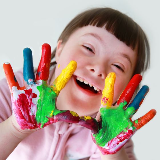 Cute little down syndrome girl with painted hands.