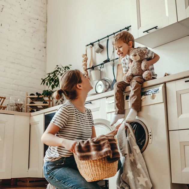 Mother doing laundry while smiling with son