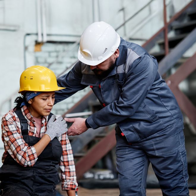 Foreman in hardhat and workwear standing by female engineer