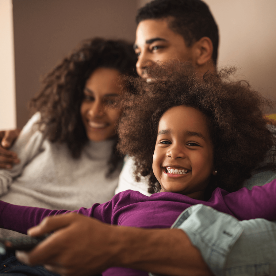 A black girl being cuddled by her parents