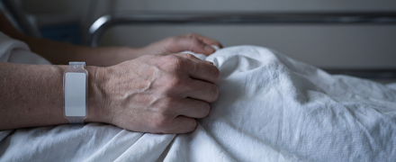 Someone in a hospital bed, holding their bed sheets