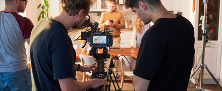 Two filmmakers filming a scene in a kitchen for their show.