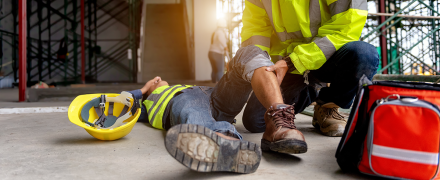 An injured construction worker receiving aid from a coworker.
