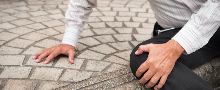 A man holding his knee after falling.