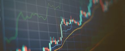 Closeup financial chart with uptrend line candlestick graph in stock market on blue color monitor background