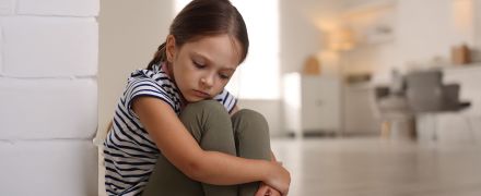 A young girl crouched down looking sad