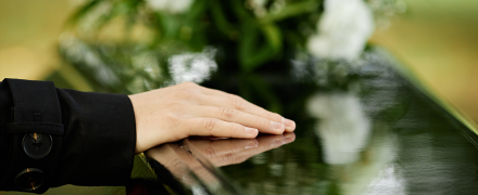 A woman resting her hand on a casket.