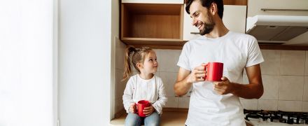 A father drinking out of a mug with his daughter.