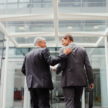 Two business men walking into an office building together