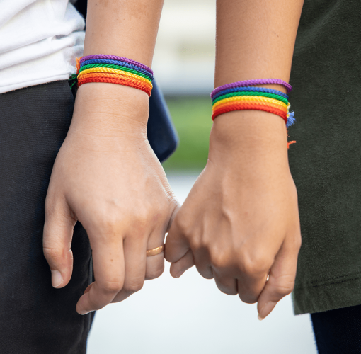 hand of LGBT women holding together with rainbow ribbon symbol