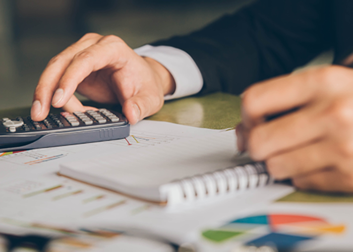 Businessman doing finances with using calculator and writing note in office.