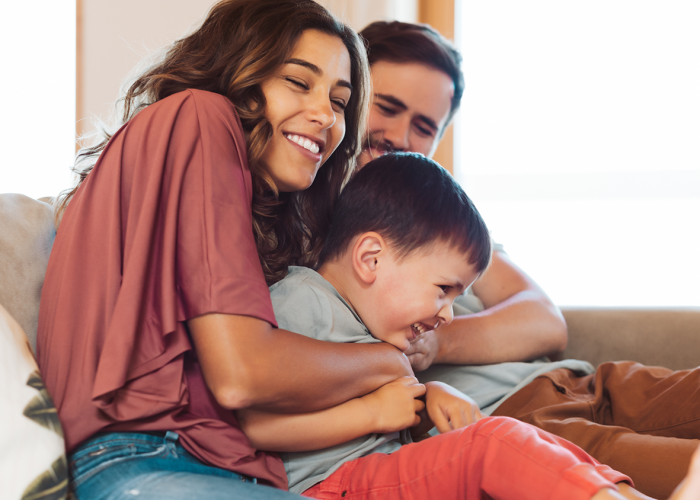 A young hispanic family laughing together on the couch.