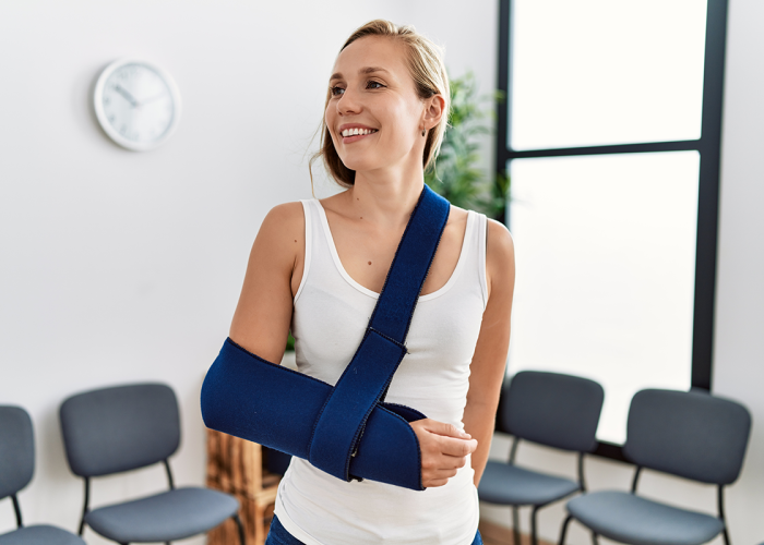 A woman smiling with her arm in a cast while she is waiting in an office.
