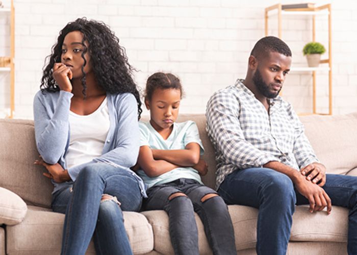 black family sitting on a couch looking upset