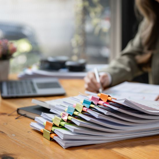Businesswoman working in Stacks of paper files for searching and checking unfinished document achieves on folders papers.