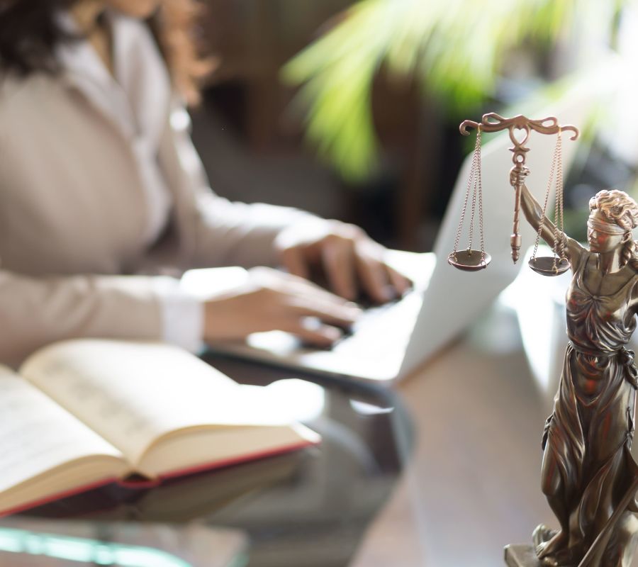 Statue of Justice with scales and lawyer working on a laptop. Legal law, advice and justice concept