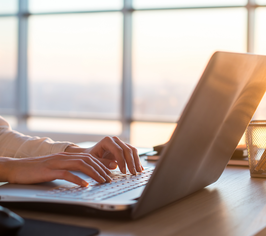 A woman typing on a laptop at sunset