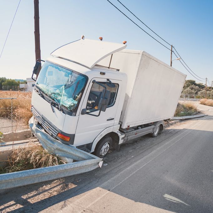 Crashed truck that hit crashed barrier on road, broken windshield, sunny day