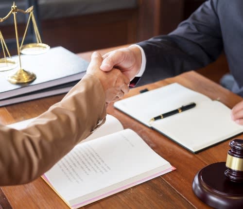 two people shaking hands over documents