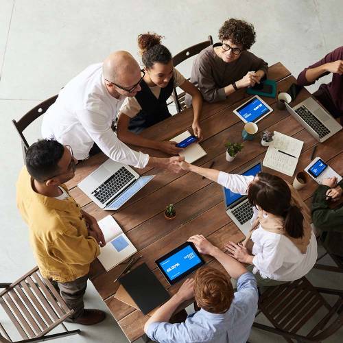 Group of people shaking hands over a meeting table