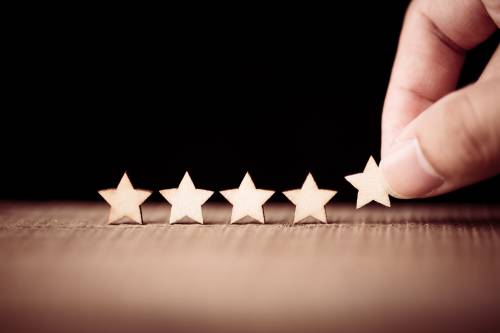 Hand placing 5 wooden stars next to each other