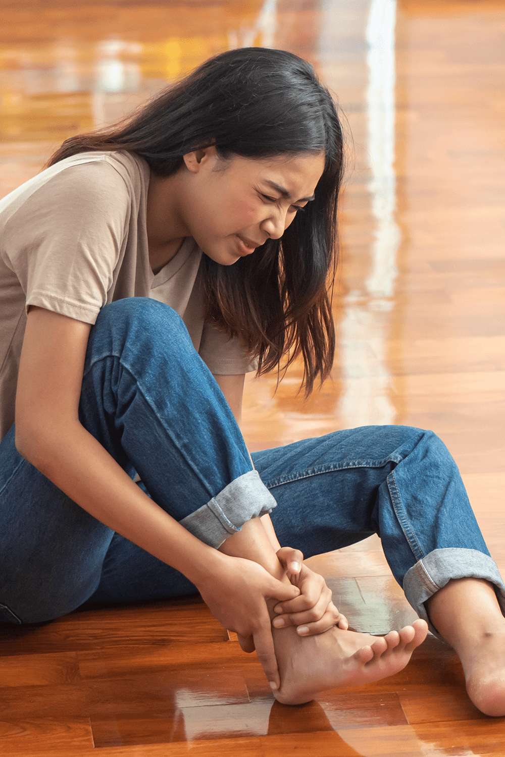 injured woman with ankle pain or foot injury; portrait of asian woman falling, having pain at her ankle; concept of wound, bruise, injury, pain from accident
