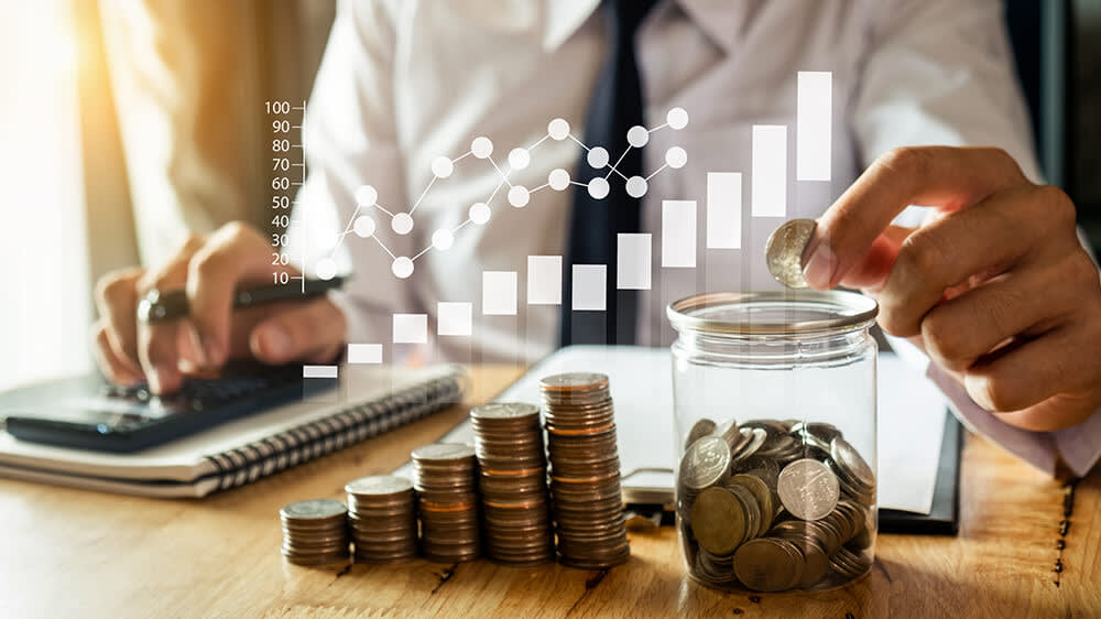 Businessman with assorted coins stacked to resemble growing wealth