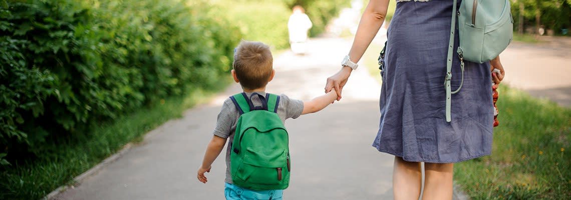 Woman walking down a path with a little boy holding her hand