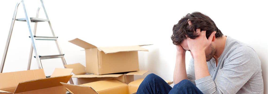 Men sitting with head in hands surrounded by boxes