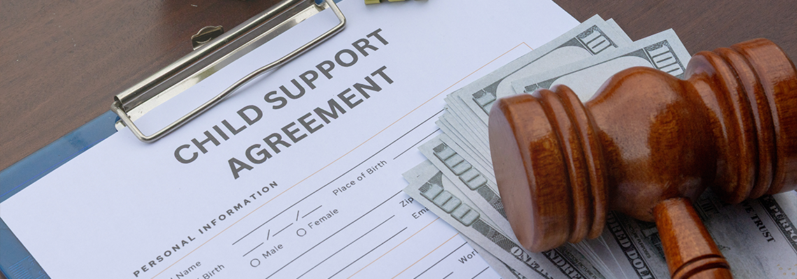 A detailed child support agreement paper on a desk with cash, a gavel