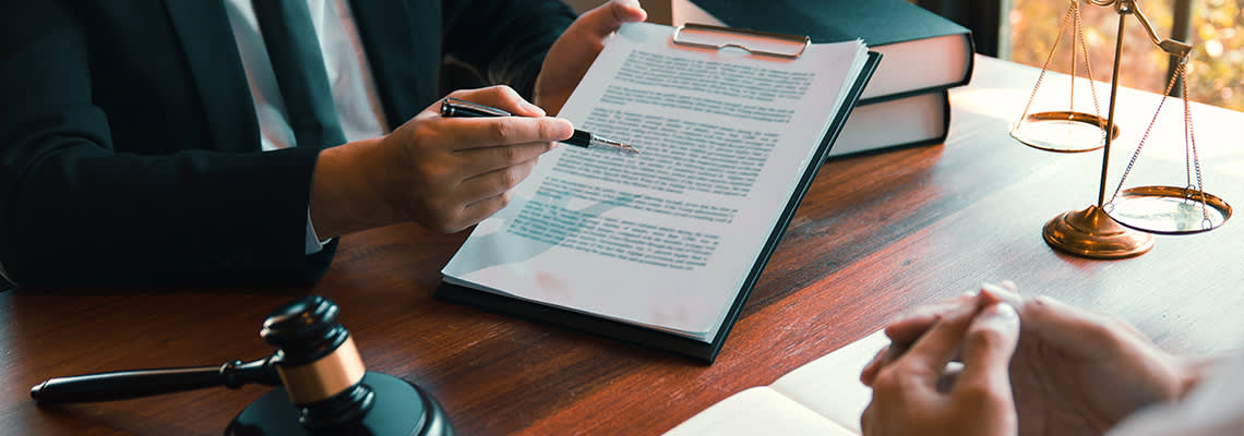 Person in suit using pen to point to clipboard
