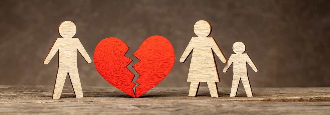 Paper cutouts of family with a heart breaking between them
