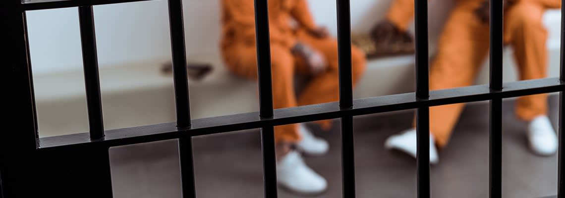 Two men sit in a jail cell