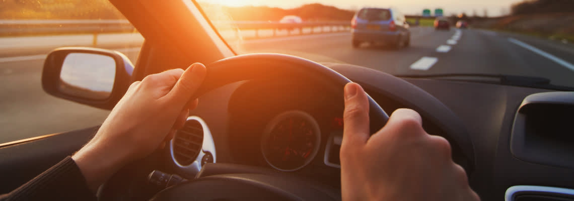 Hands of car driver on steering wheel