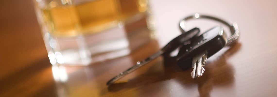 Keys sitting next to a glass of alcohol