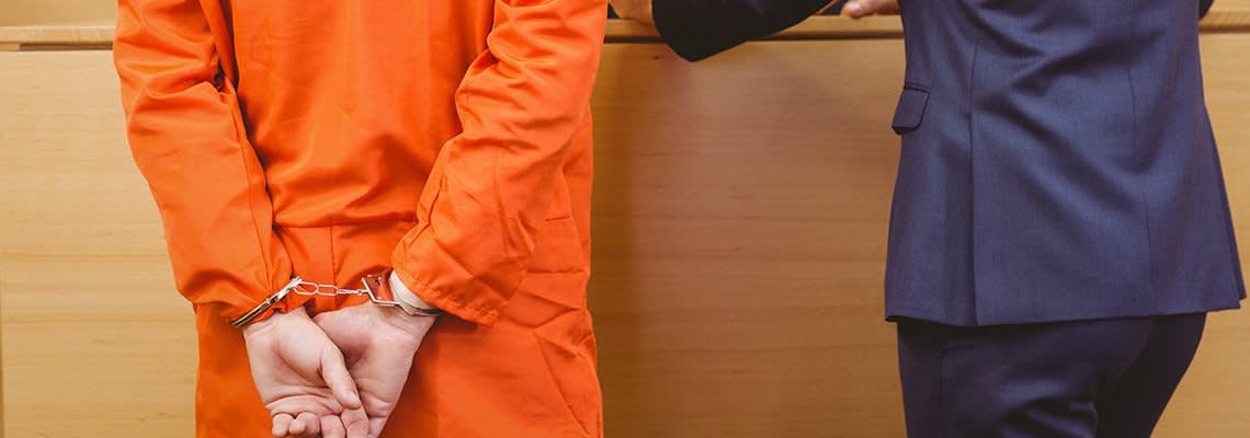 A prisoner and their lawyer stand in a court room