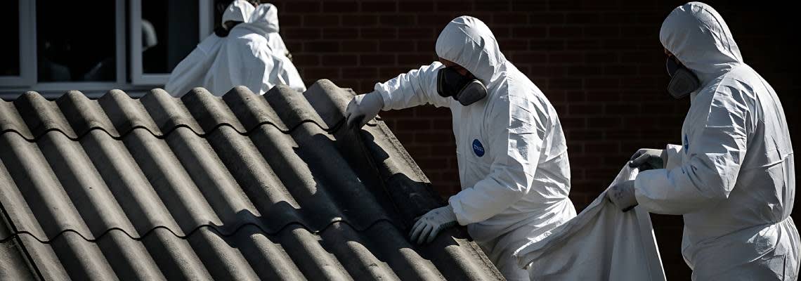 Asbestos removal workers in protective suits carefully handling hazardous materials